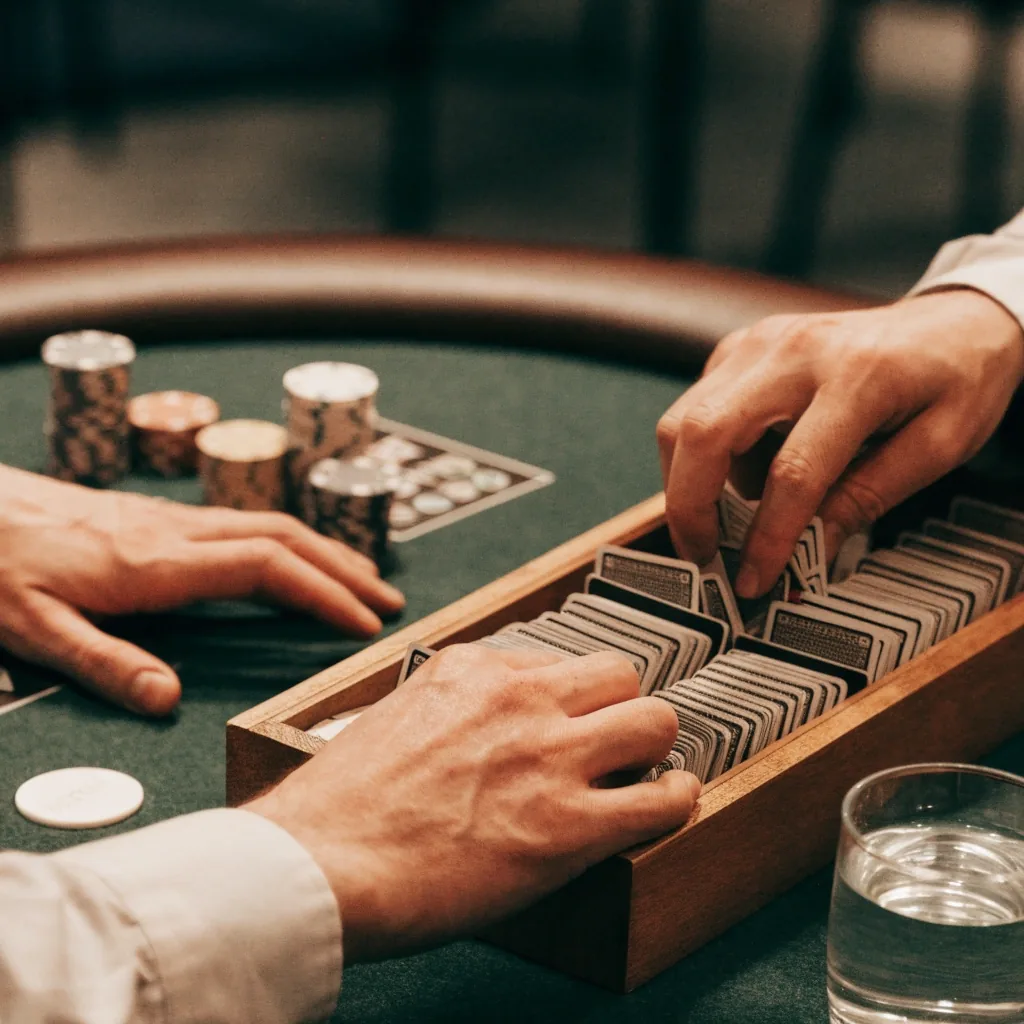 Dealer u stolu v pokerovém prostoru, ruce u karet a žetonů